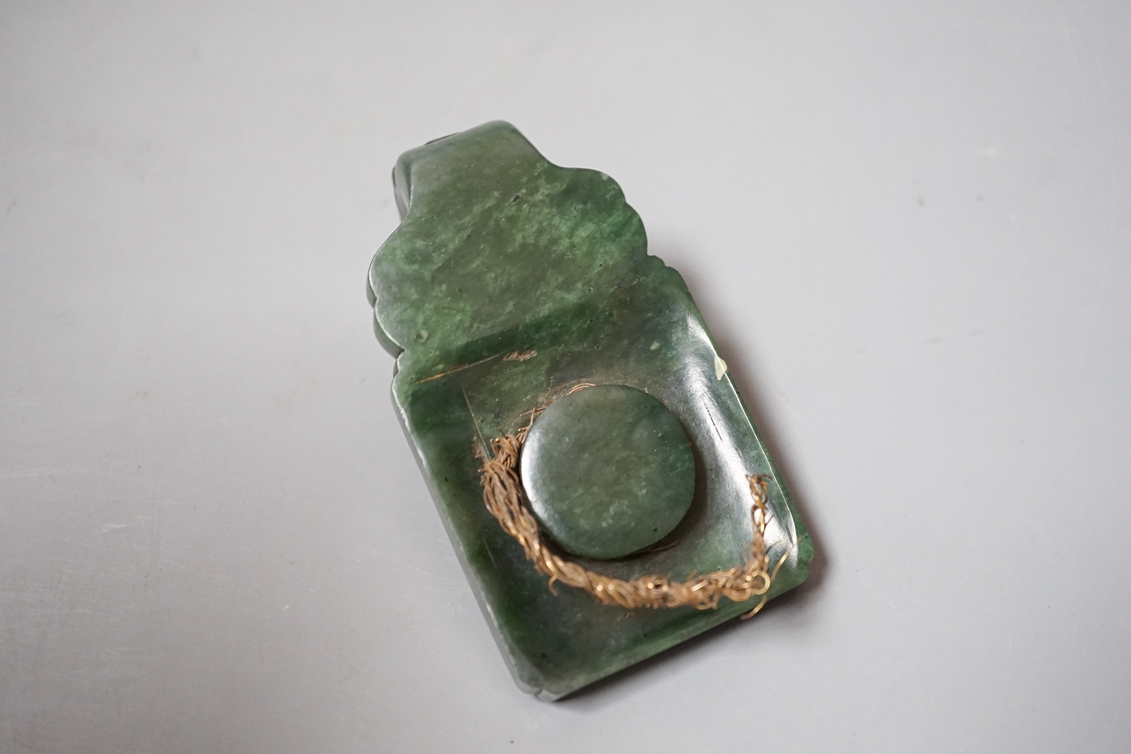 A Chinese spinach green jade belt hook, 19th century, in archaistic style, carved in relief with a chi-dragon, with a dragon head handle, 9cm